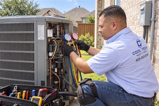 Technician repairing an outdoor AC condenser unit at a Dallas home
